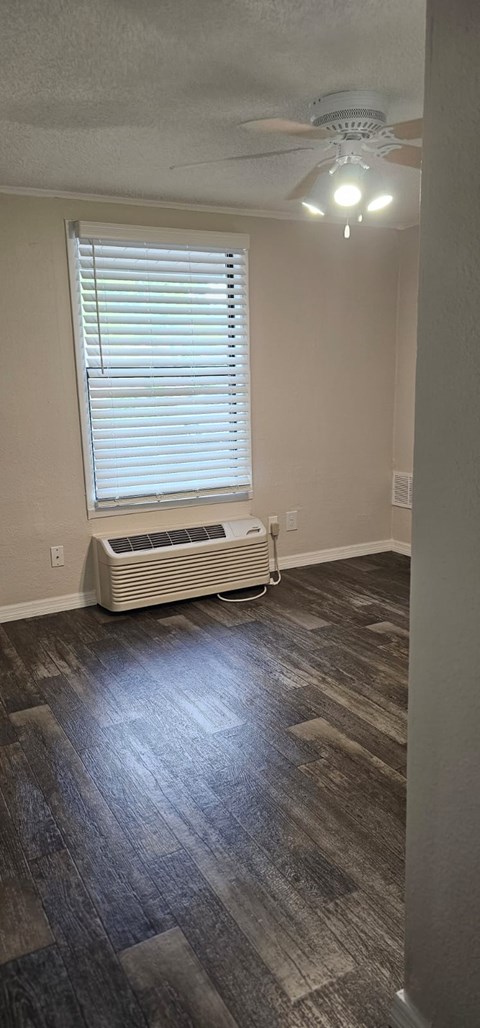A room with a ceiling fan and a window with blinds.