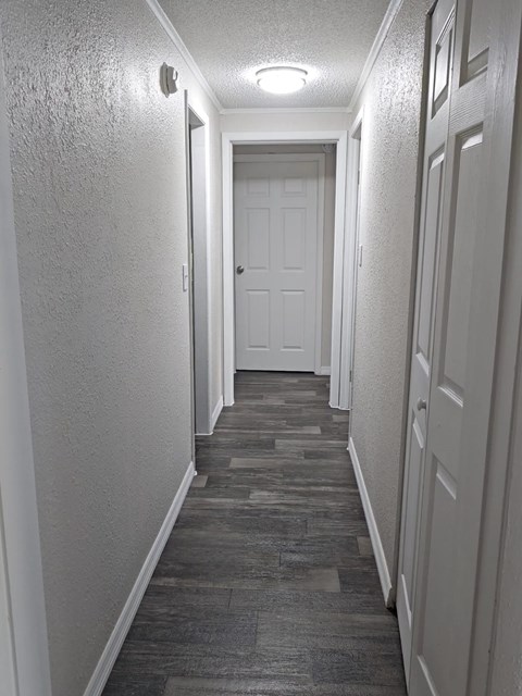 A long hallway with a white door at the end.