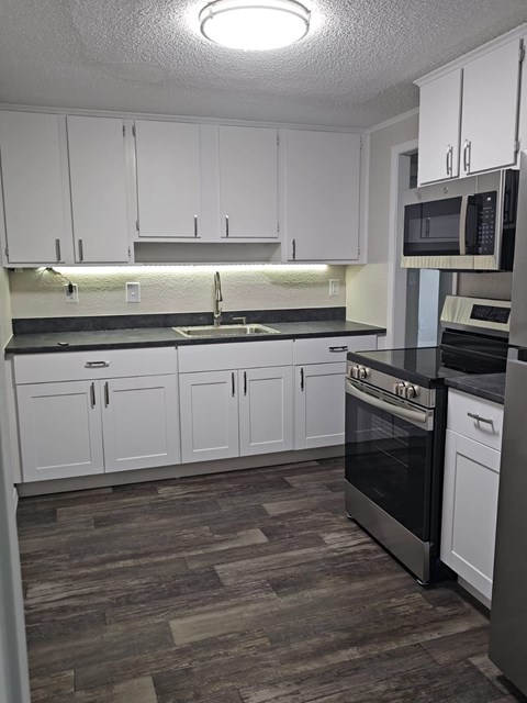 A kitchen with white cabinets and a black stove top oven.