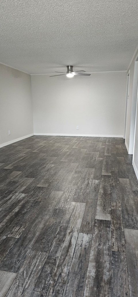 A room with a ceiling fan and wooden flooring.
