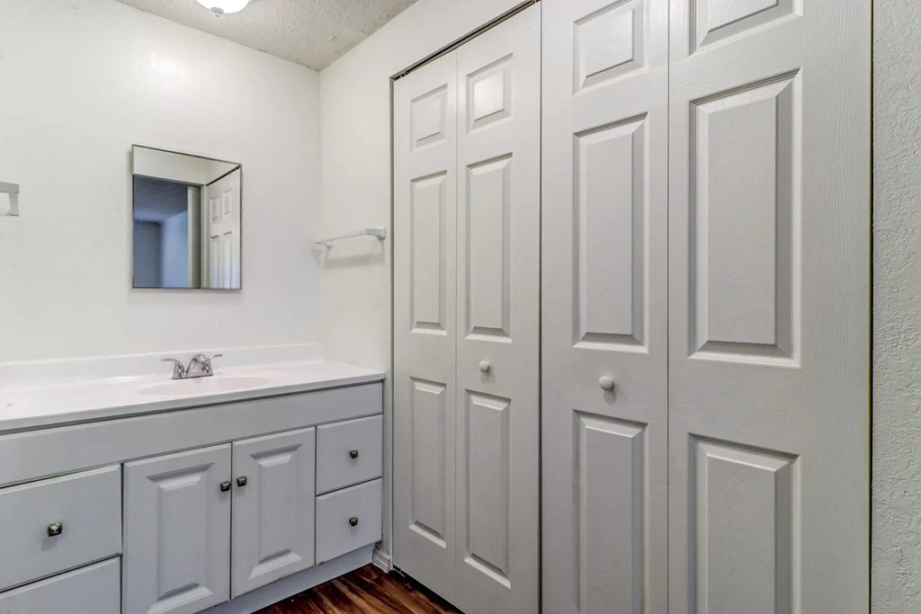 a bathroom with white cabinets and a sink and a mirror