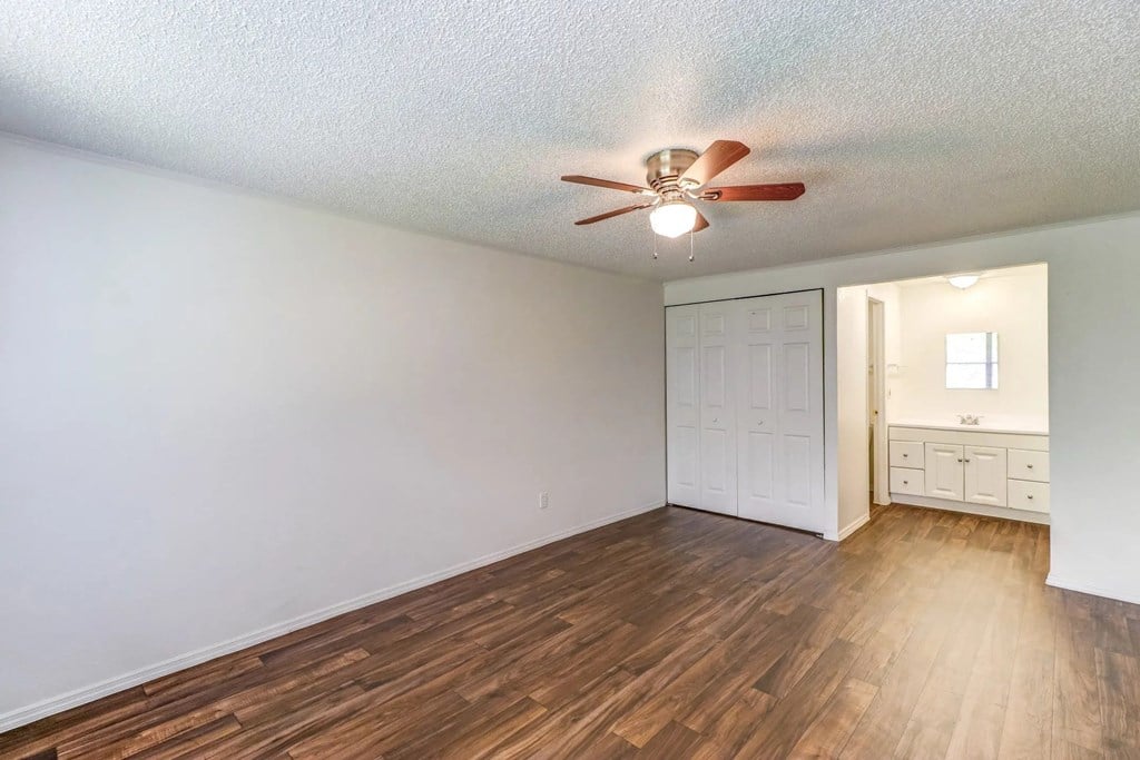 an empty living room with a ceiling fan and a closet