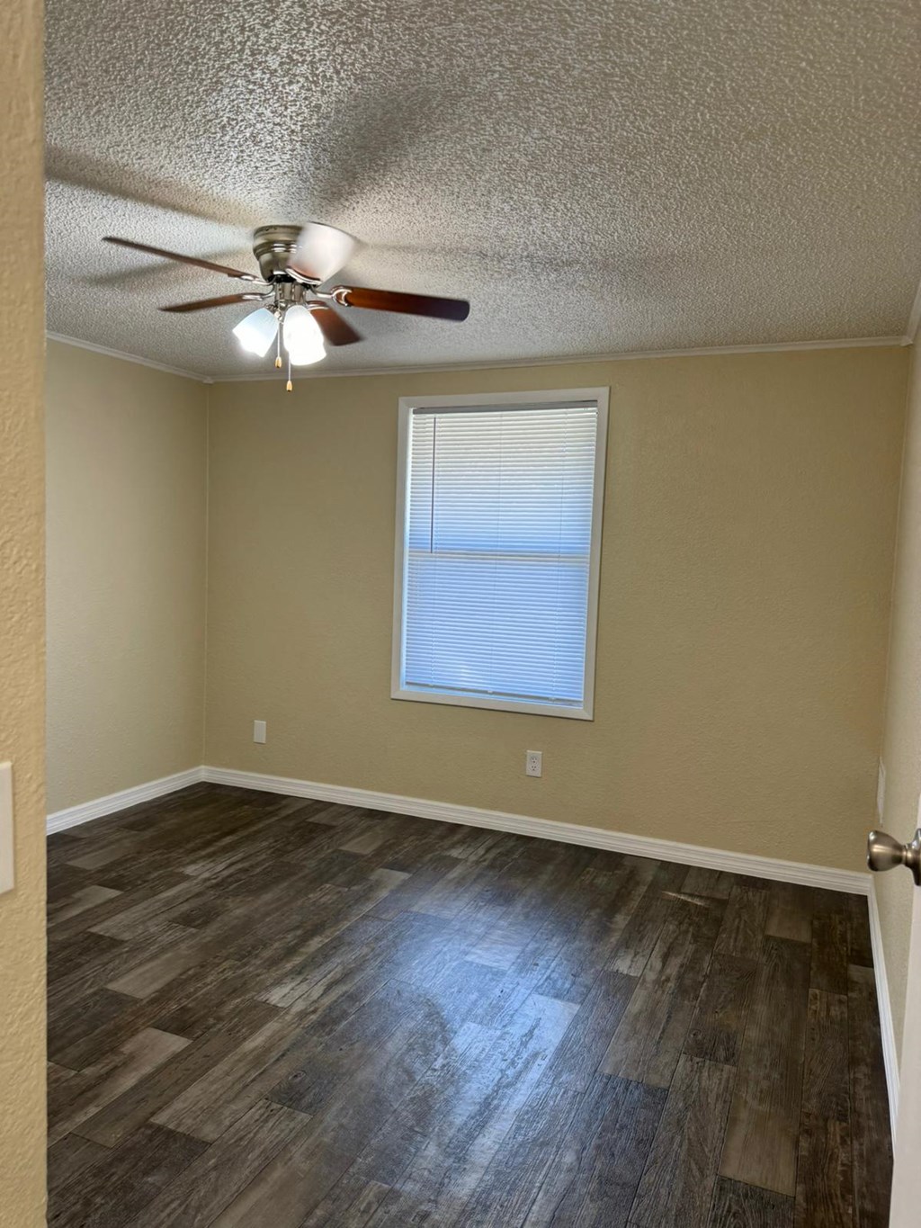 an empty room with a ceiling fan and a window