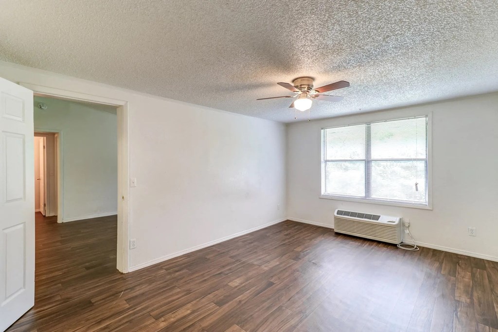 an empty living room with a ceiling fan and a window