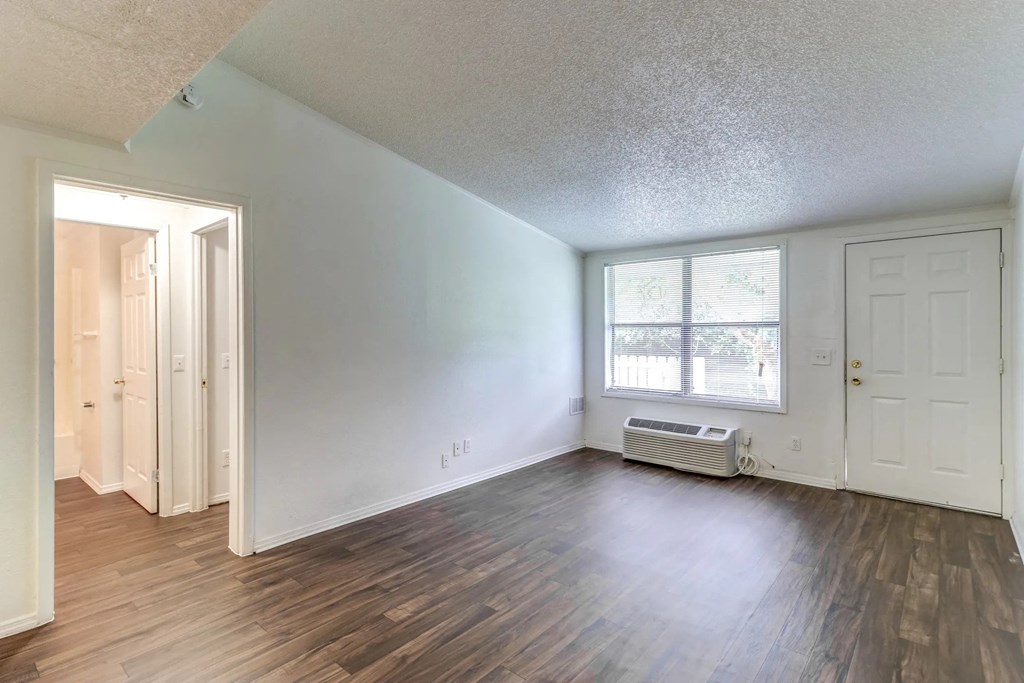 an empty living room with wood flooring and a window
