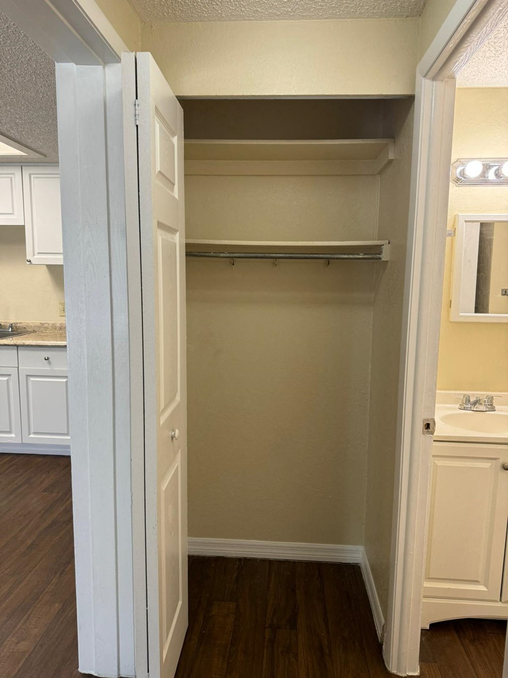a walk in closet in a kitchen with white cabinets