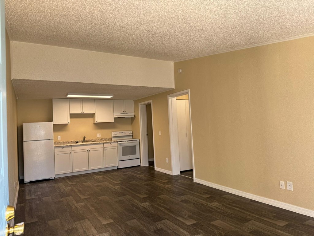 an empty kitchen with white appliances and a hard wood floor