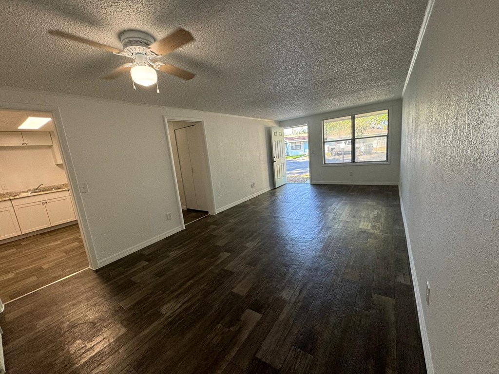 an empty living room and kitchen with a ceiling fan