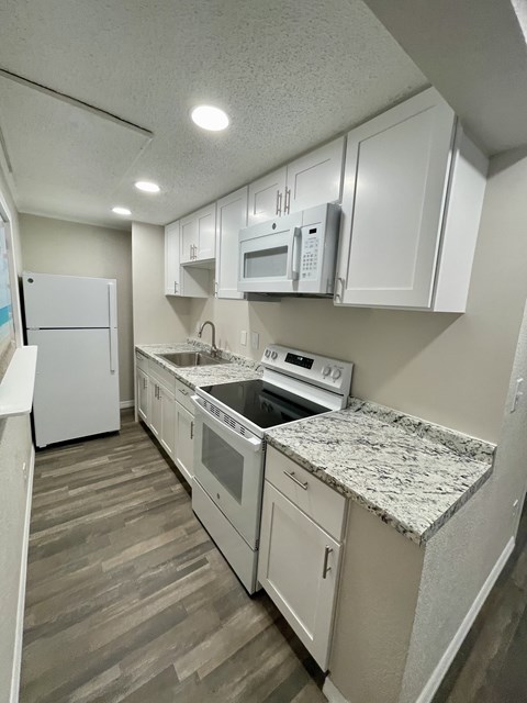 A kitchen with white cabinets and appliances.
