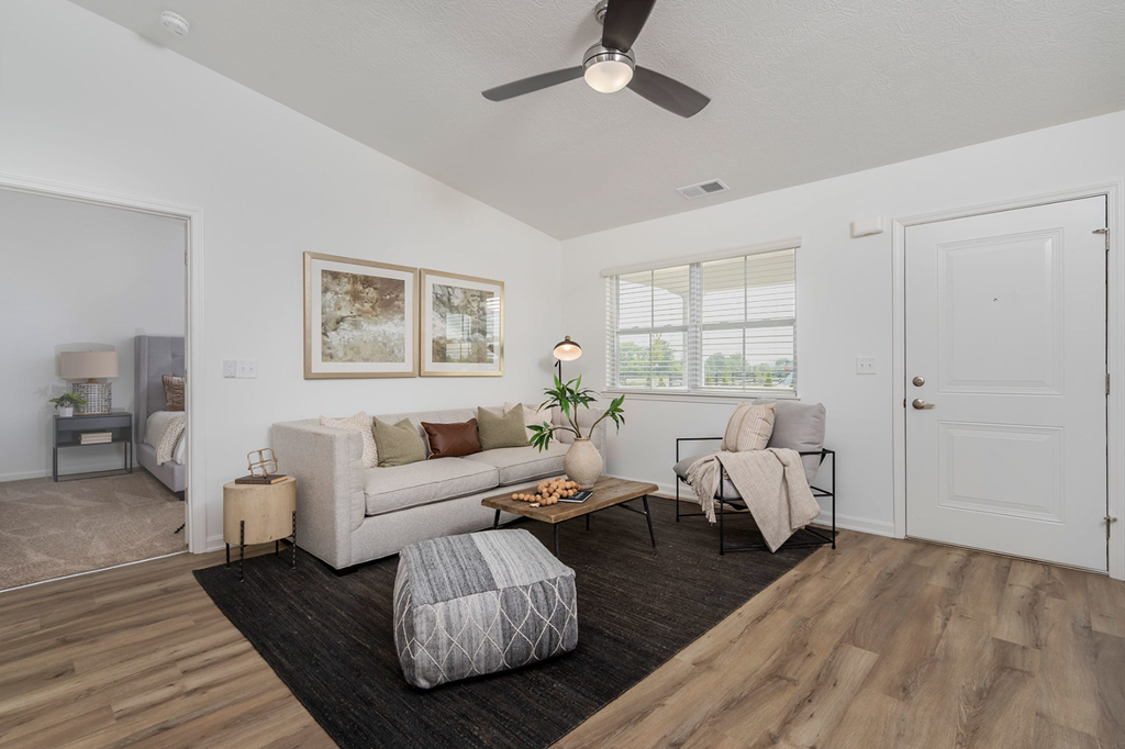 A living room with a white couch, a coffee table, and a ceiling fan.