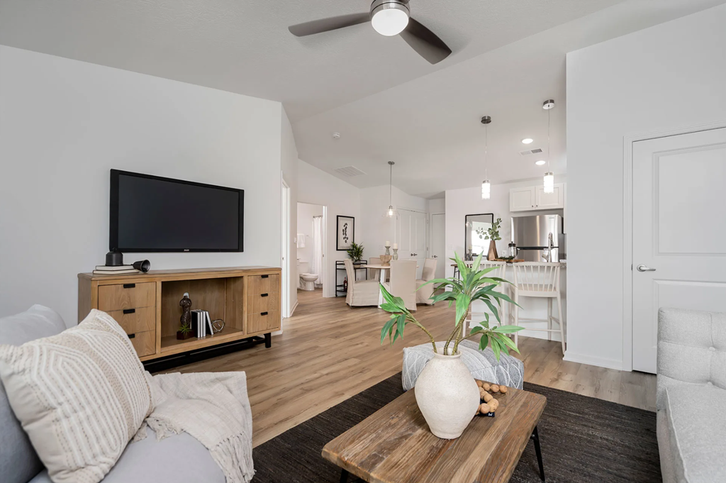 A living room with a grey couch, a wooden coffee table, and a flat screen TV on a wooden cabinet.