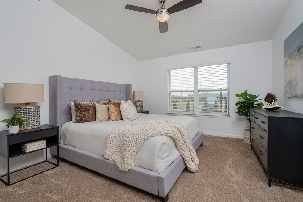 A bedroom with a bed, nightstand, and a ceiling fan.