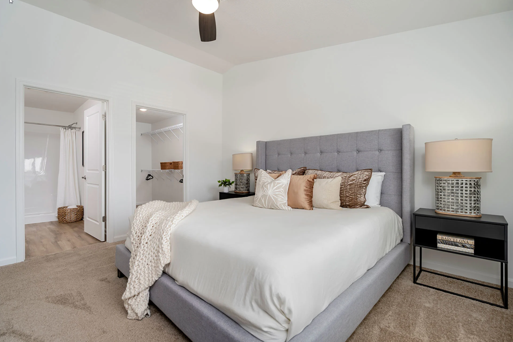 A bedroom with a large bed and a ceiling fan.