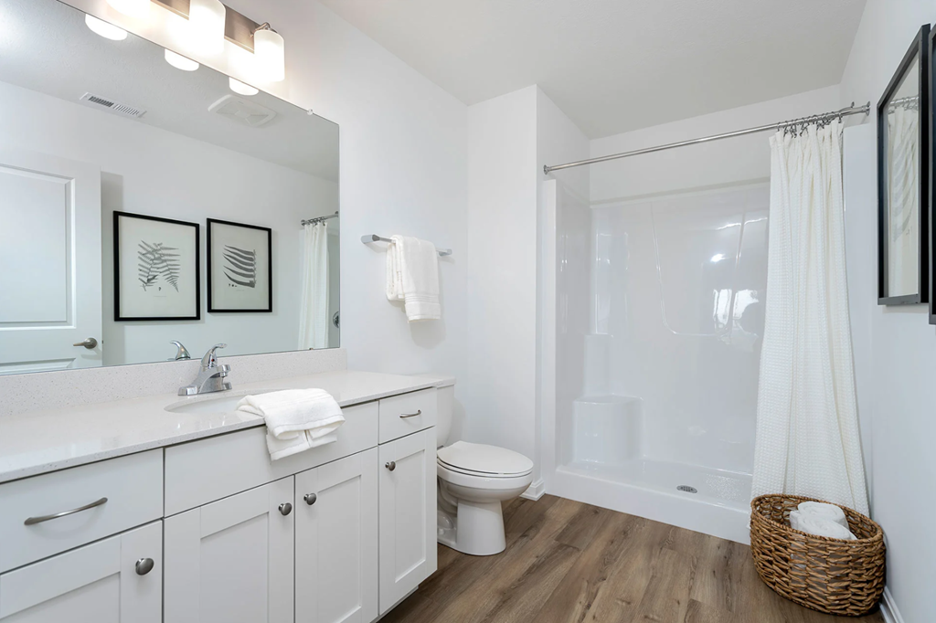 A white bathroom with a toilet, sink, and mirror.