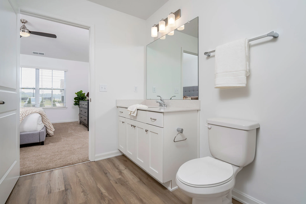 A white bathroom with a toilet, sink, and mirror.