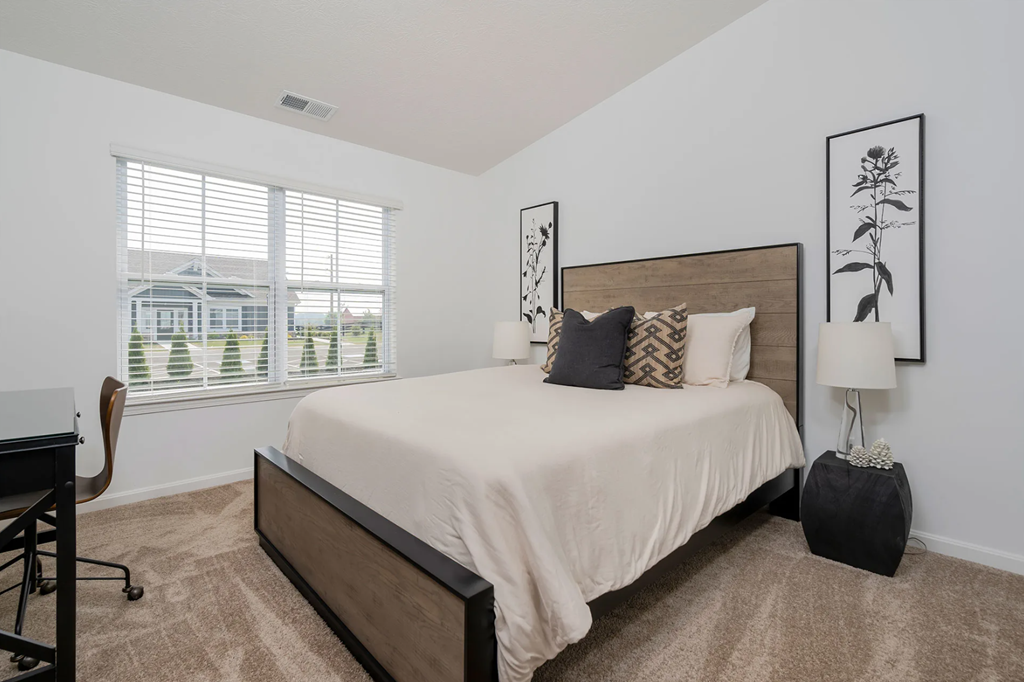 A bedroom with a large bed and a window with blinds.