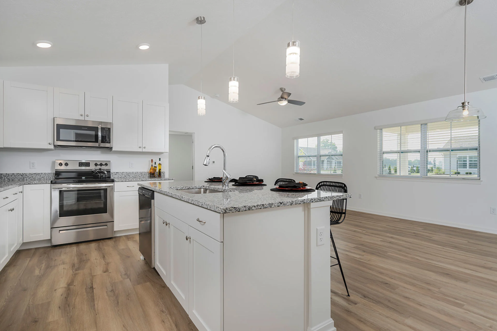 A modern kitchen with white cabinets and a wooden floor.