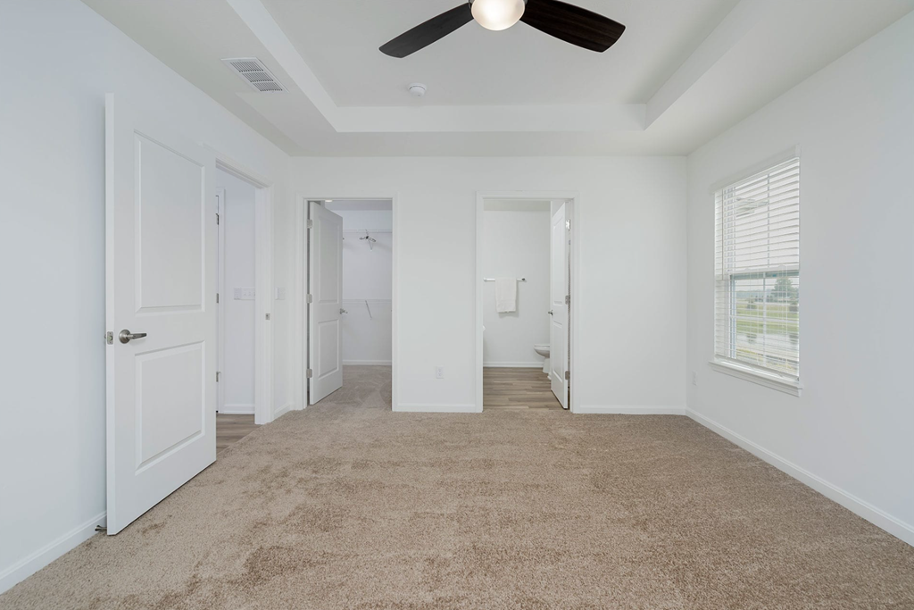 A room with a ceiling fan and carpeted floor.