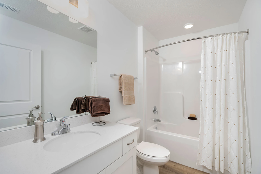 A white bathroom with a towel hanging on the wall.