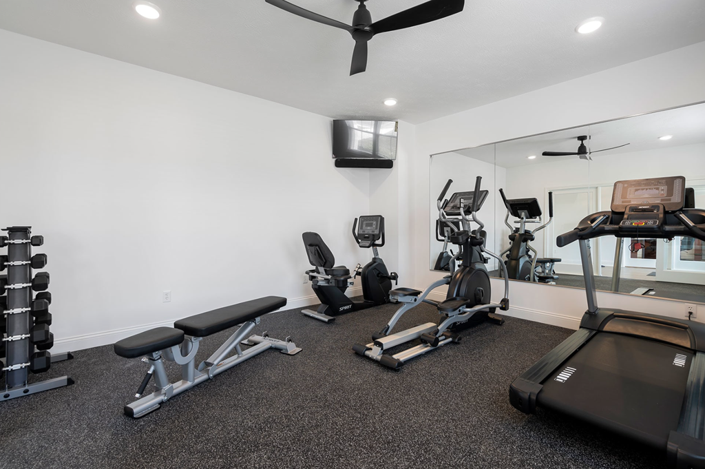 A spacious home gym with a variety of equipment including a treadmill, weights, and a bench.