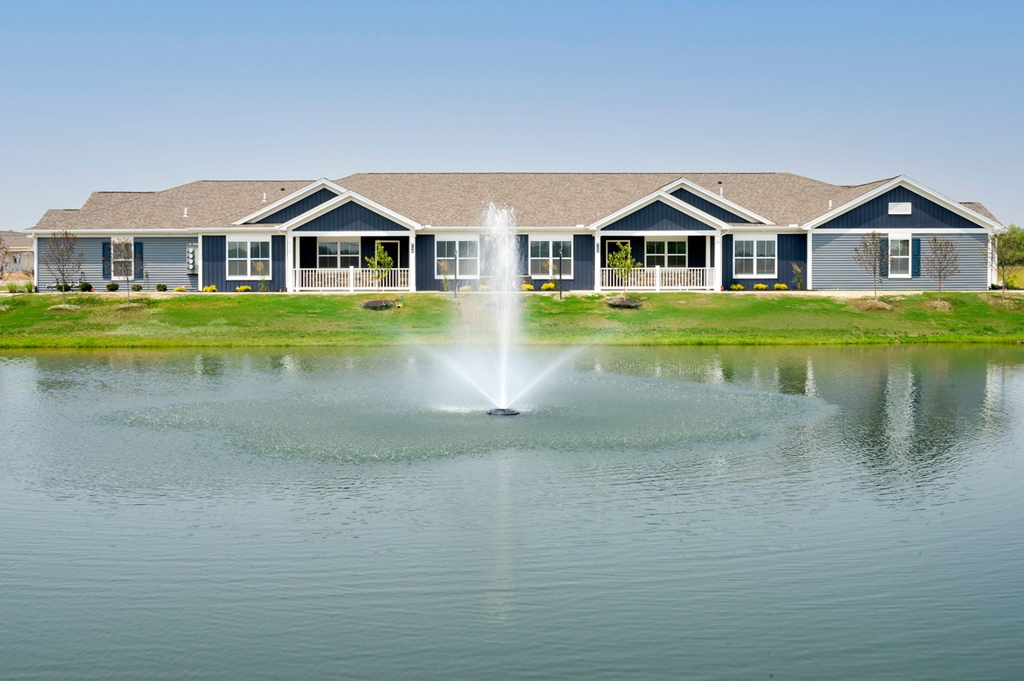 A house with a blue fence and a water fountain in front.