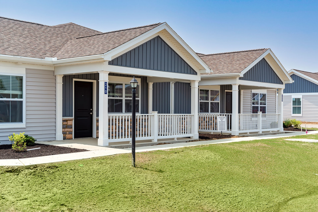A house with a grey and white exterior and a brown roof.