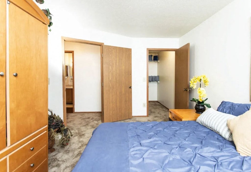 A bedroom with a blue bedspread and a wooden wardrobe.