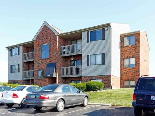 an apartment building with cars parked in a parking lot