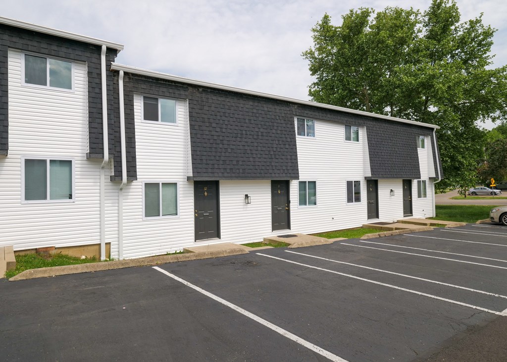 a white building with a black roof and a parking lot