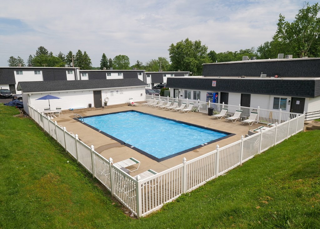 an aerial view of a resort style pool in front of a white fence