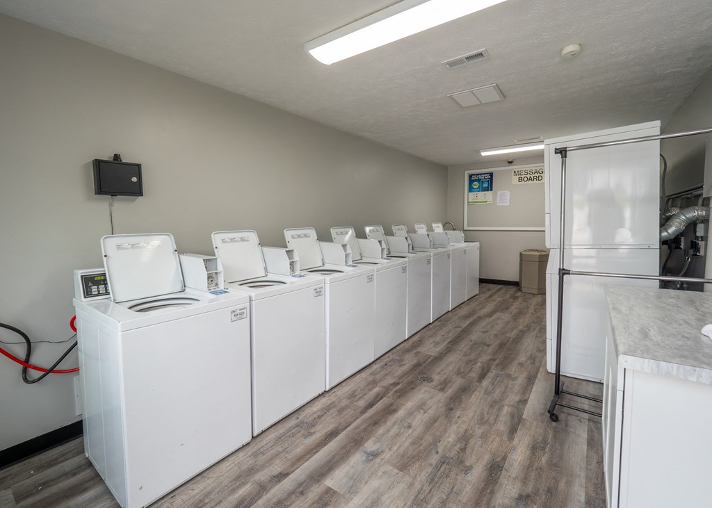 a row of washers and dryers in a room with wood flooring