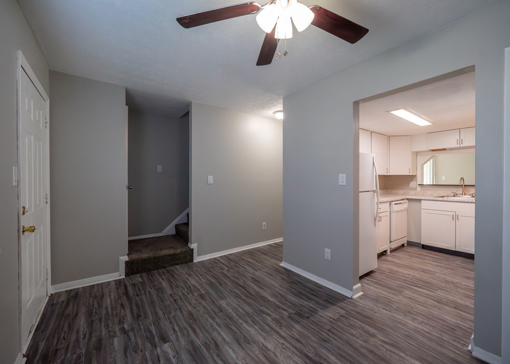 an empty living room and kitchen with a ceiling fan