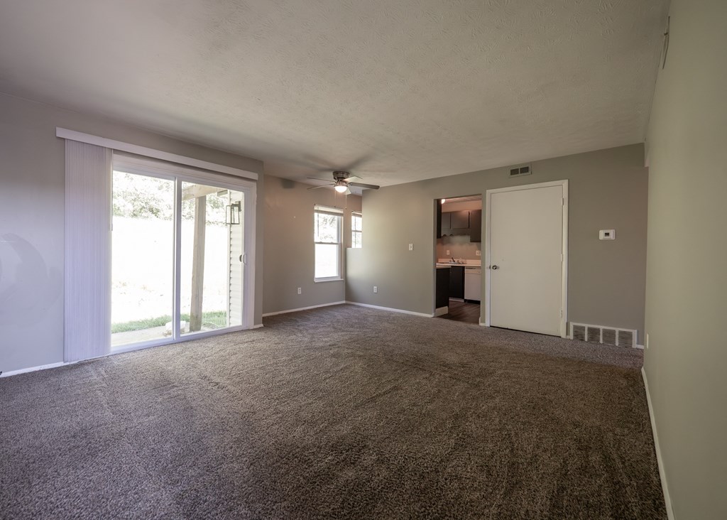 an empty living room with carpet and sliding glass doors