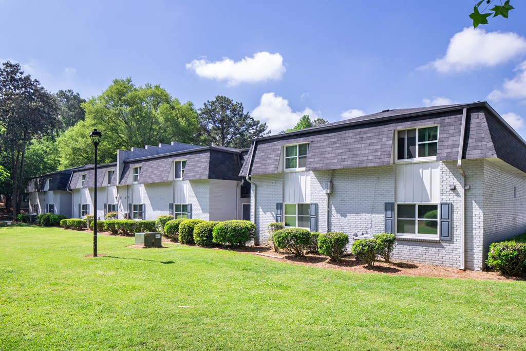 A white building with a black roof and a green lawn in front.