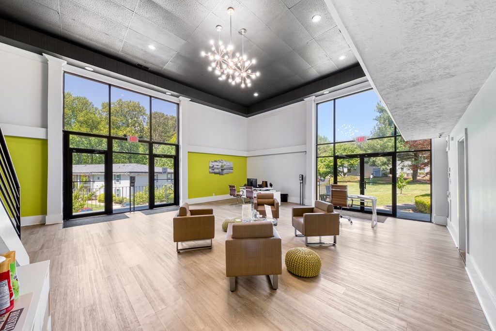 A spacious room with a high ceiling and a large window overlooking a green area.