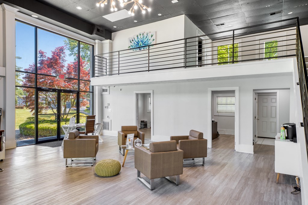 A modern living room with a balcony and a view of trees.