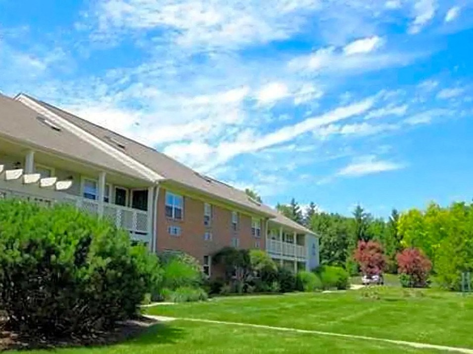 an apartment building with a green lawn and a blue sky