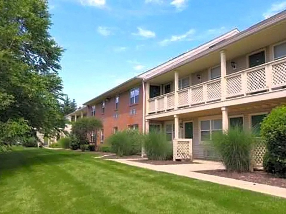 an apartment building with a green yard and grass
