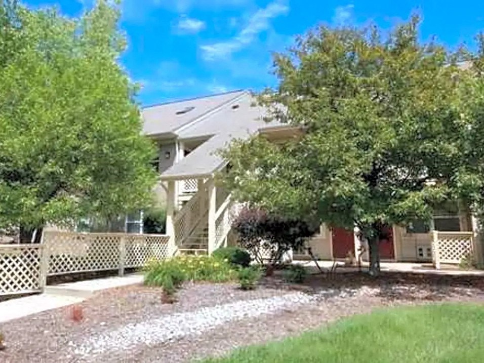 a house with a yard and trees in front of it