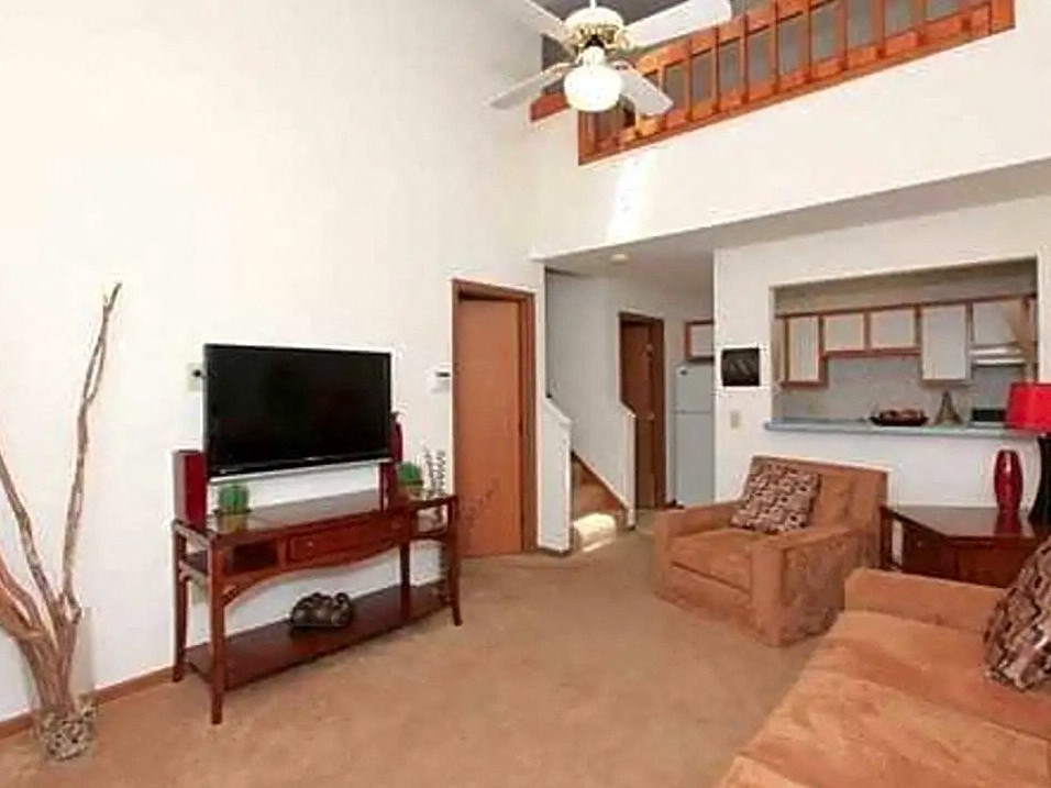 a living room with a ceiling fan and a tv