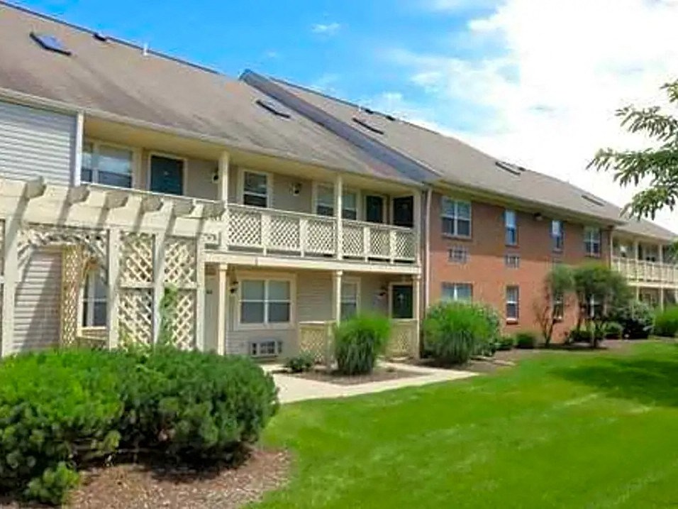 an apartment building with a balcony and a yard