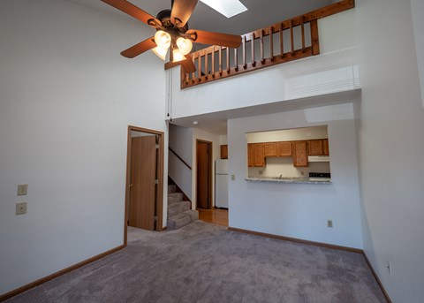 A living room with a ceiling fan and a staircase.