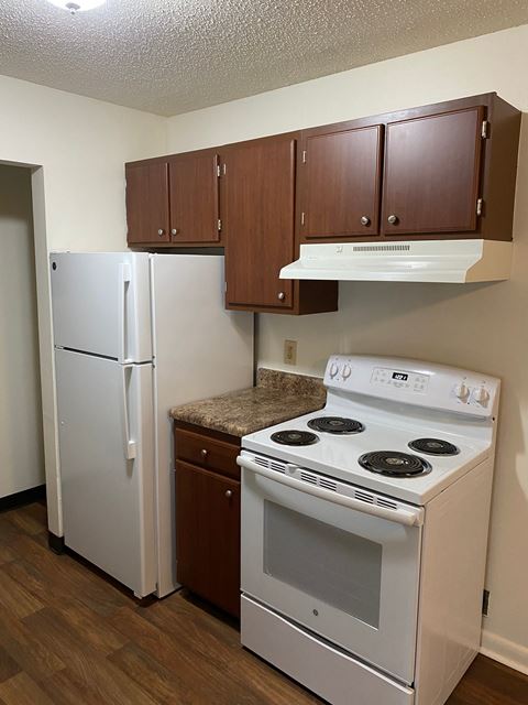 a kitchen with a white stove and refrigerator and wooden cabinets