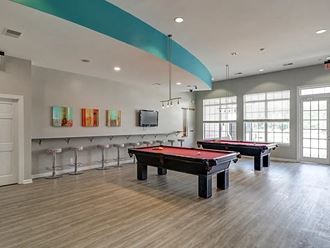 a game room with two pool tables and bar stools