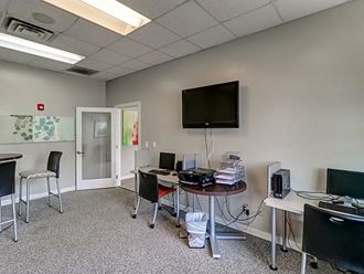 a conference room with two desks and a television on the wall