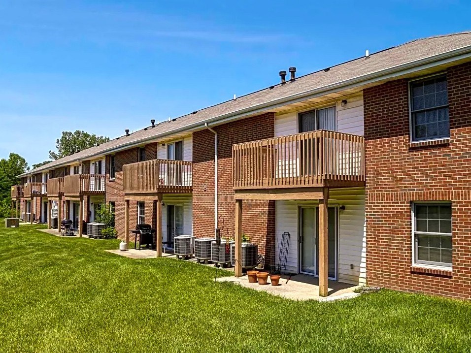 a row of brick apartments with balconies and grass