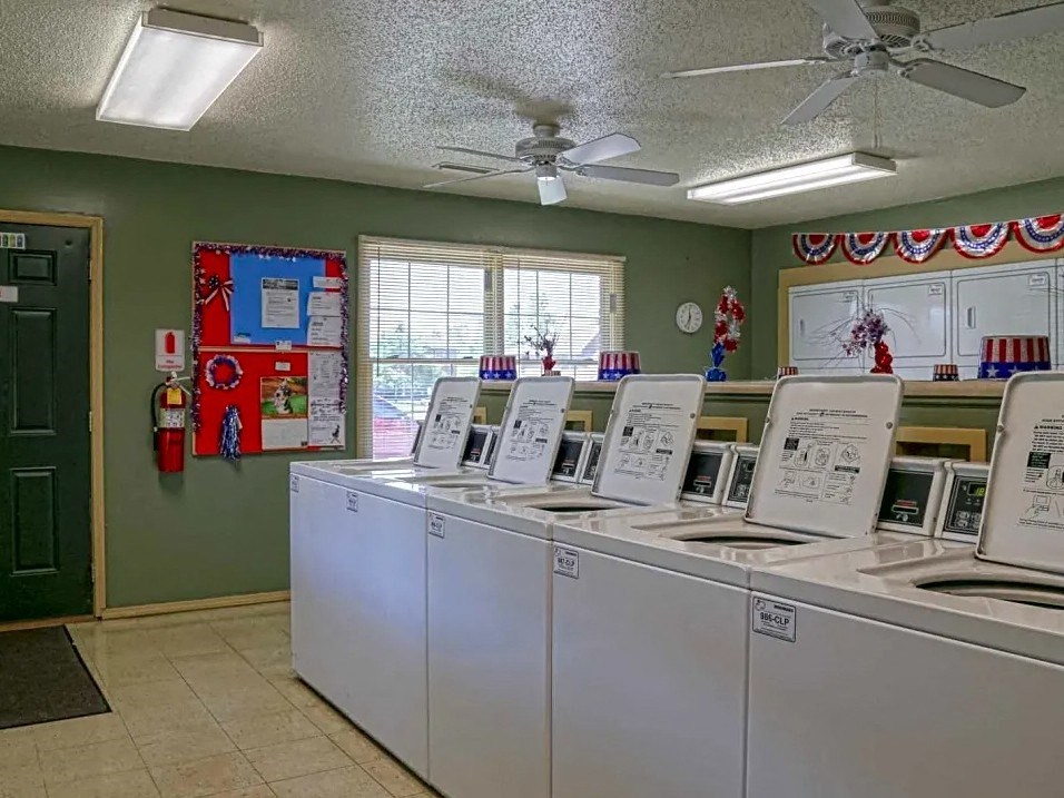 a laundromat with four machines and a ceiling fan