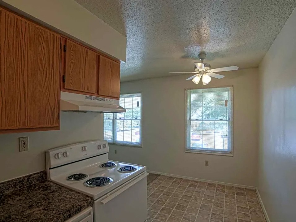 a kitchen with a stove and a ceiling fan