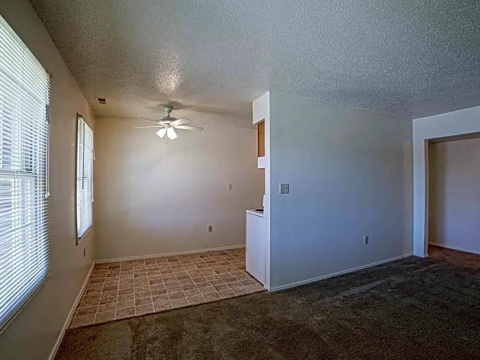 an empty living room with a ceiling fan and a window