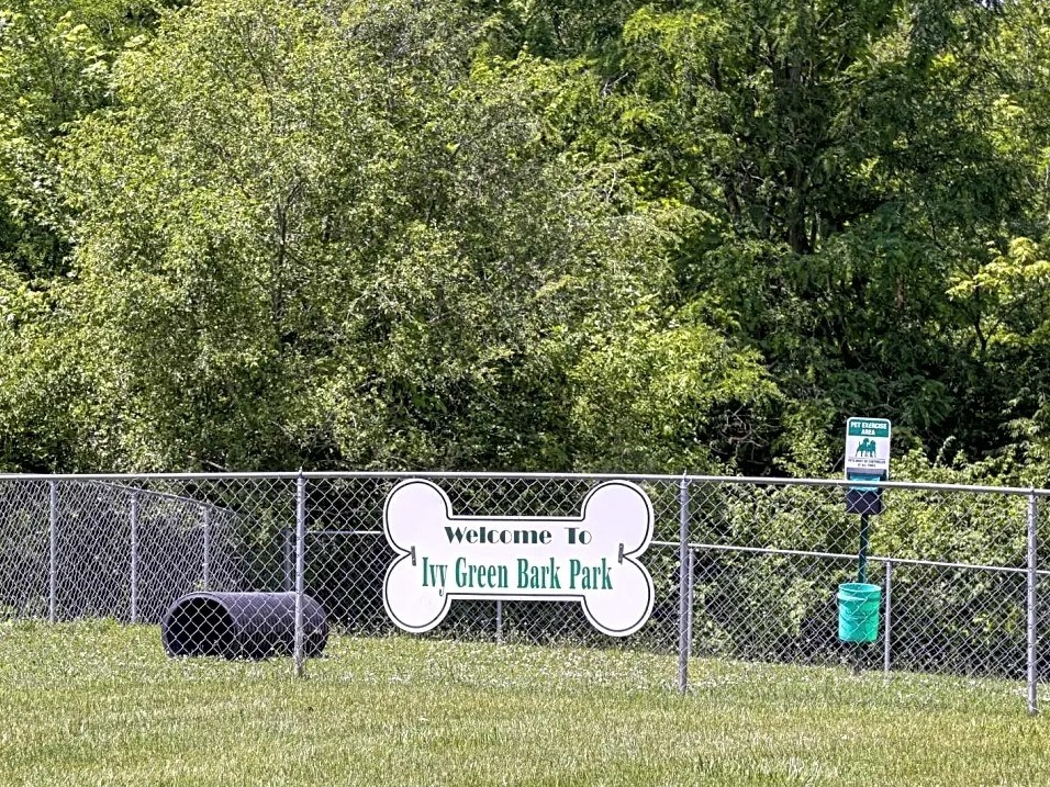 a sign on a chain link fence in a green ball park